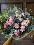 Medium bouquet of pink roses and greenery on a wooden surface