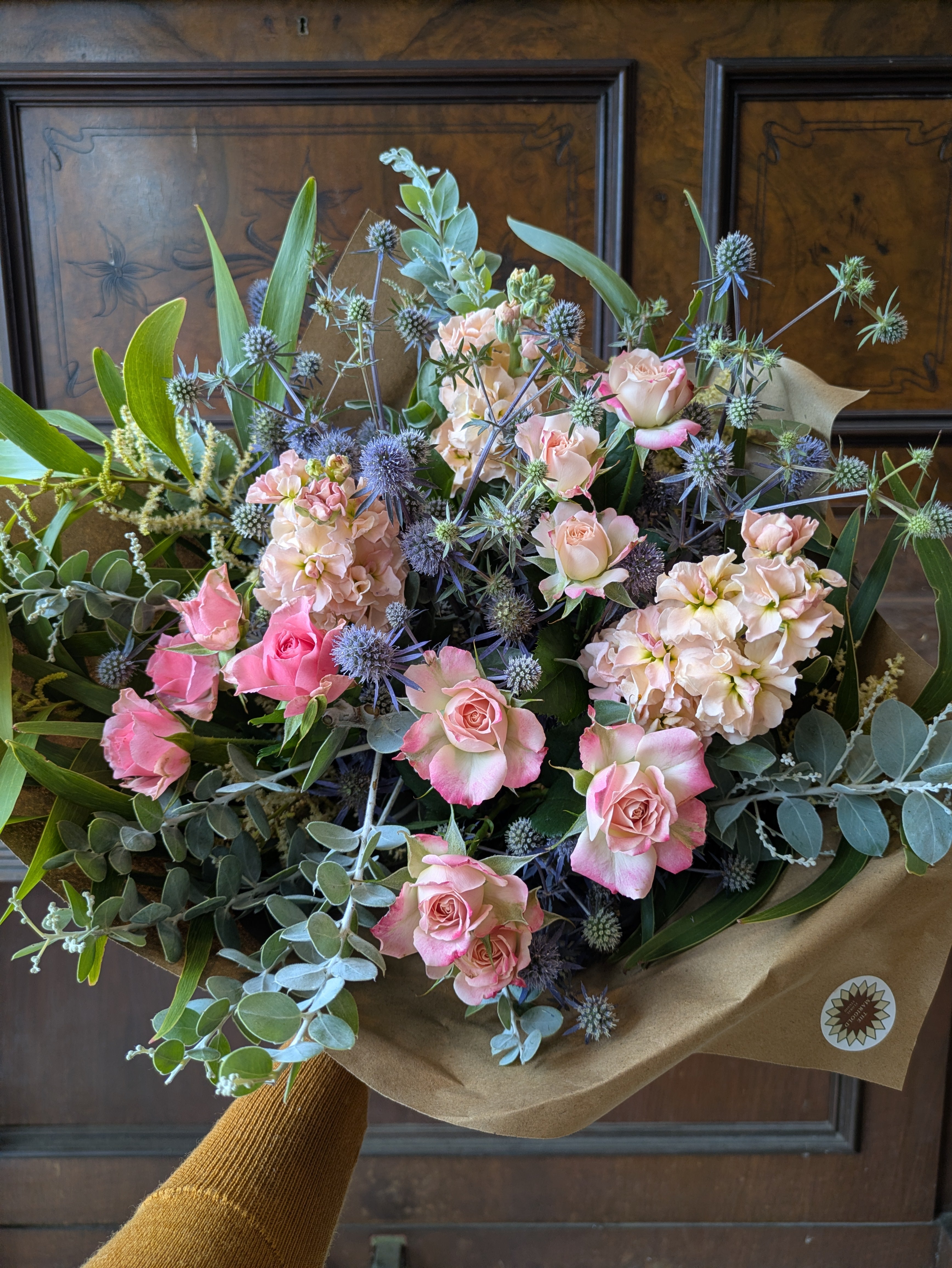 Medium bouquet of pink roses and greenery on a wooden surface