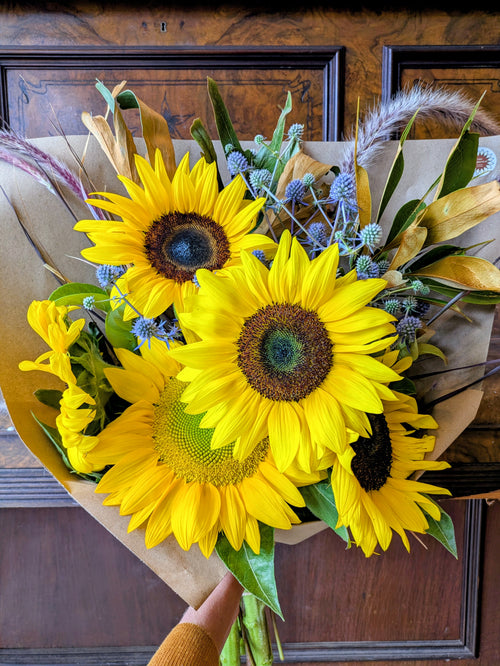 Bouquet of sunflowers held in front of a wooden door