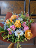 Warm and colourful bouquet of flowers on a wooden surface with a decorative background.