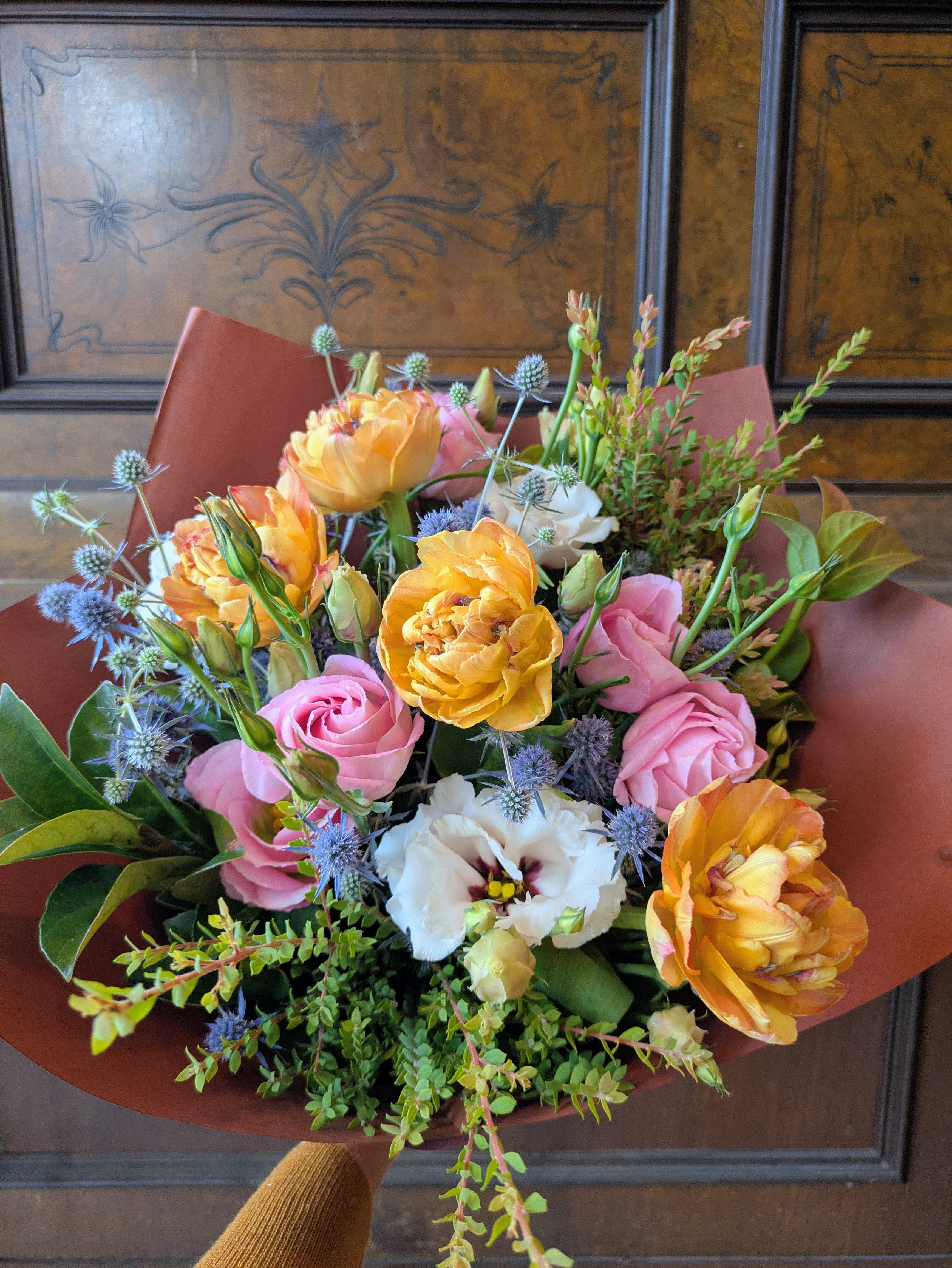 Warm and colourful bouquet of flowers on a wooden surface with a decorative background.